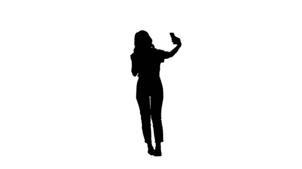 Silhouette Meraviglioso modello femminile bianco che fa selfie mentre cammina — Foto Stock