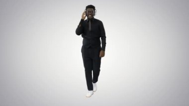 Gülümseyen Afro-Amerikan kulaklıklı adam, yürürken müzik dinliyor ve arka plandaki kameraya bakıyor..