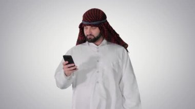 Arap adam akıllı telefonuyla internette sörf yapıyor ya da grafiksel arka planda yürürken mesajlaşıyor..