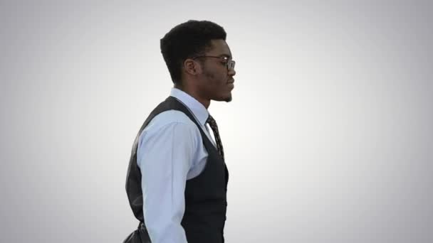 안경을 쓴 젊은 아프리카계 미국인 사업가가 교 차 한 배경 위를 자신있게 걷고 있다. — 비디오