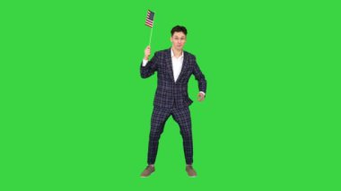 Resmi takım elbiseli genç adam yeşil ekranda Amerikan bayrağı ile tuhaf bir şekilde dans ediyor, Chroma Key.