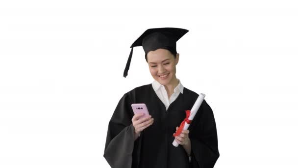 Счастливая выпускница с дипломом и смс на телефоне на белом фоне. — стоковое видео