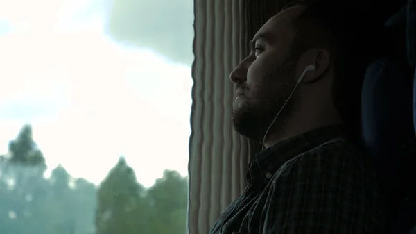Uomo serio vicino al finestrino del treno che ascolta musica. — Foto Stock