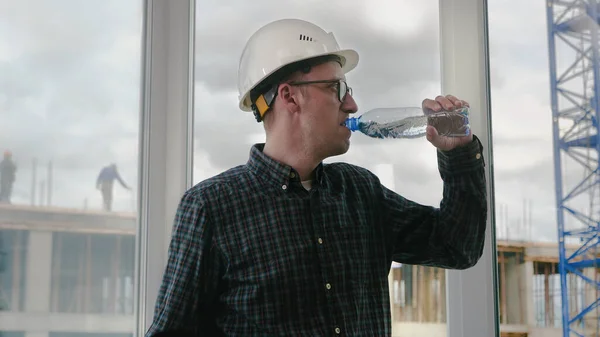 Construction worker drinking water on a location site.