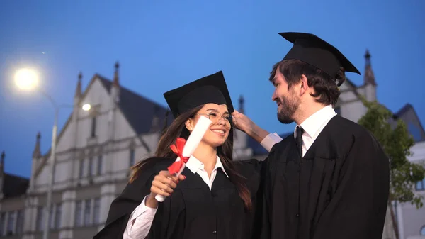 Grappige afgestudeerden in academische jurken dansen en rotzooien na het afstuderen. — Stockfoto