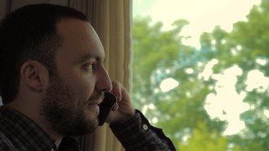 Trende otururken telefonda konuşan çekici bir adam..