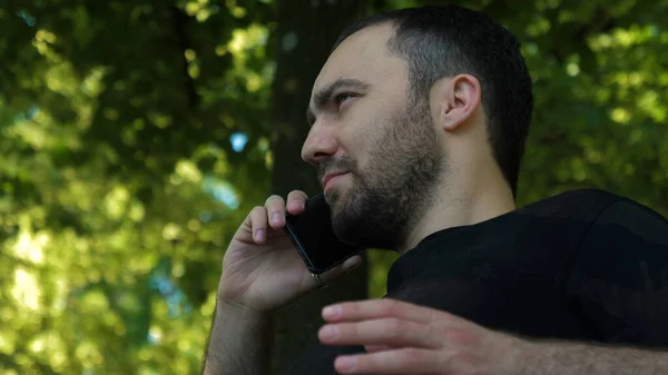 Poważny facet rozmawiający przez telefon w parku.. — Zdjęcie stockowe
