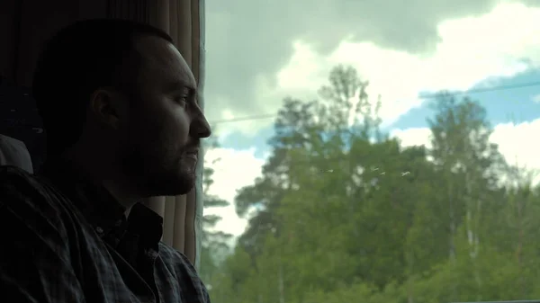 Homme caucasien dans un train en journée, regardant par la fenêtre. — Photo