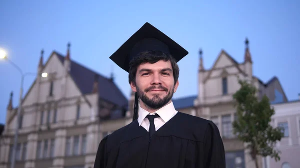 Attractive smiling male graduate standing and looking at camera.