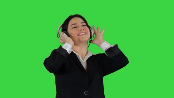 Young business woman listening to music in headphones and dancing on a Green Screen, Chroma Key. — Stock Video