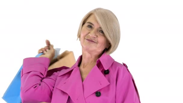 Gyönyörű idős nő árok kabát gazdaság bevásárló táskák fehér háttér. — Stock videók