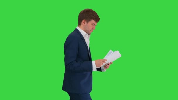 Homme d'affaires sérieux lisant des documents ou un rapport tout en marchant sur un écran vert, Chroma Key. — Video