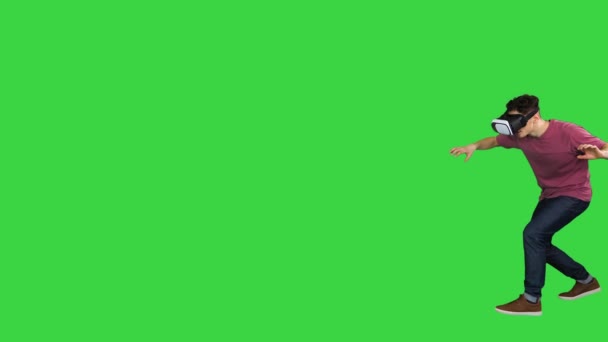 Homem em óculos de realidade virtual percorrendo o perigoso mundo virtual em uma tela verde, Chroma Key. — Vídeo de Stock