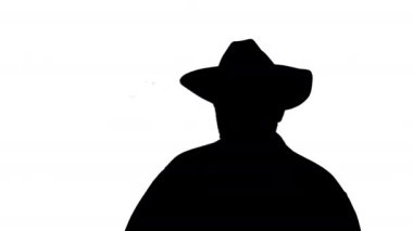 Kovboy şapkalı siluet koruyucu güneş gözlüğü takıyor ve kameraya gülümsüyor..