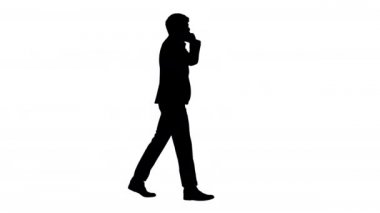 Siluet Genç işadamı yürürken telefonda konuşuyor.