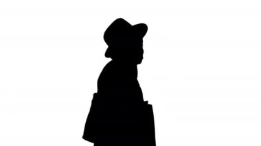 Büyük beden örgü ve şapkalı Afrikalı kız alışveriş torbalarıyla yürürken telefonla konuşuyor, Alpha Channel.