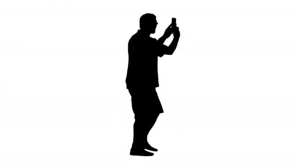 Silhouette Ευτυχισμένος ανώτερος γενειοφόρος τουρίστας με τα πόδια και τη λήψη φωτογραφιών με το τηλέφωνό του. — Αρχείο Βίντεο
