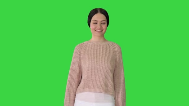 Ontspannen jonge vrouw lopen naar en kijken met een glimlach op de camera in casual stijl kleren op een groen scherm, Chroma Key. — Stockvideo