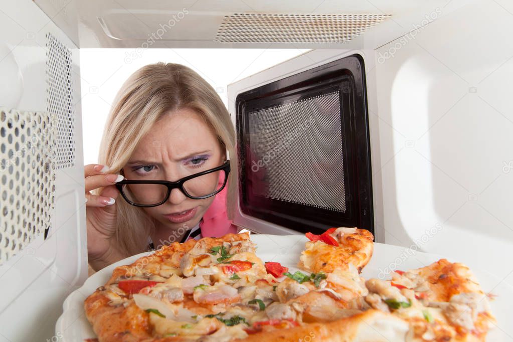 Attractive girl opening a microwave