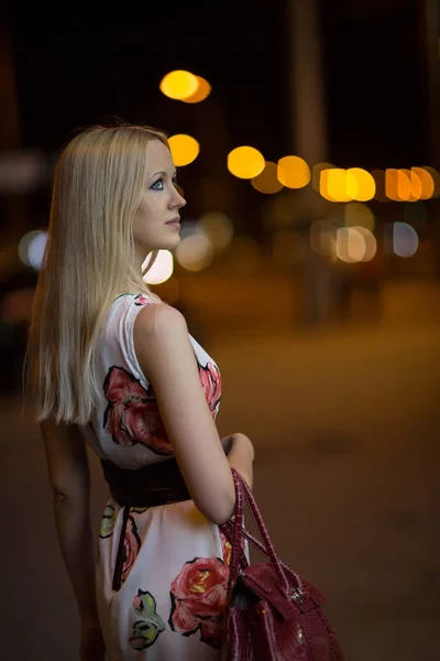 漂亮的年轻金发女孩走过一条夜城街道 — 图库照片