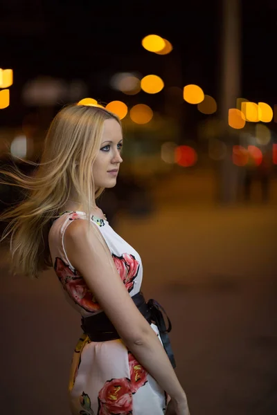 漂亮的年轻金发女孩走过一条夜城街道 — 图库照片