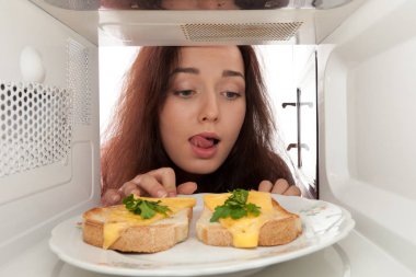 Tost bir mikrodalga ve yalamak üzerinde seyir çekici kız
