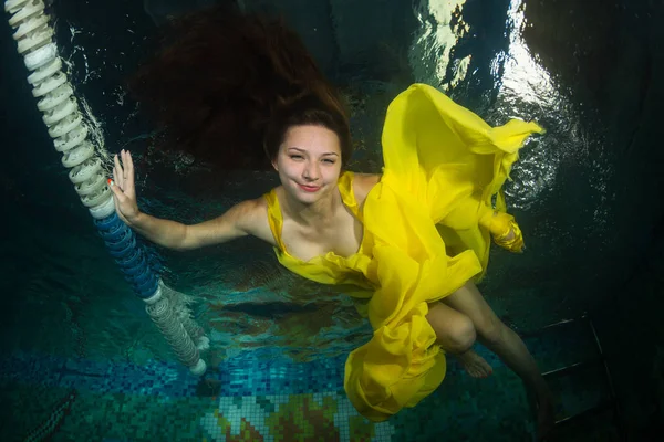 Graceful girl swimming underwater in a swimming pool.