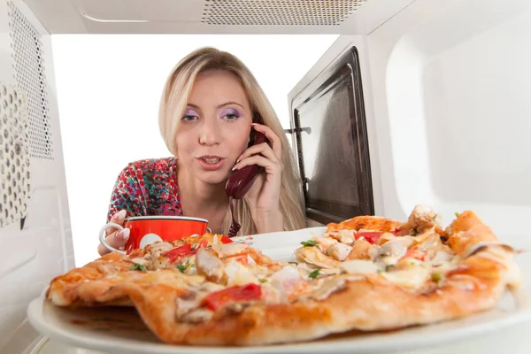 女孩准备在微波炉里吃披萨 — 图库照片