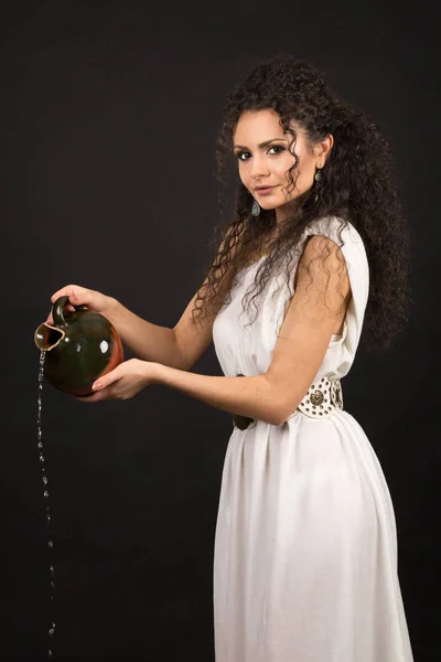 Chica Rizada Una Toga Griega Vertiendo Agua Una Jarra — Foto de Stock