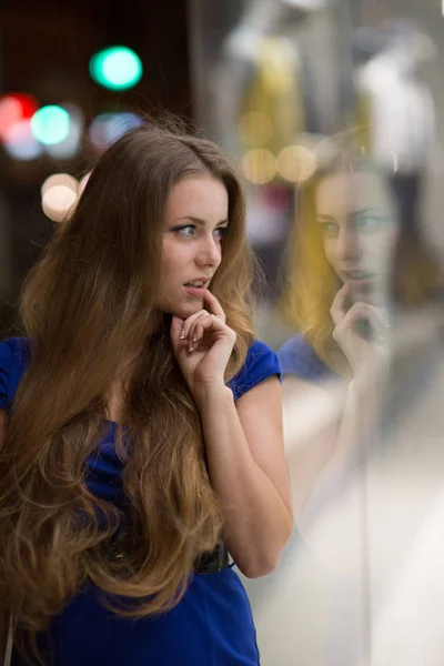 Beautiful girl looking in the shop window on the night city street