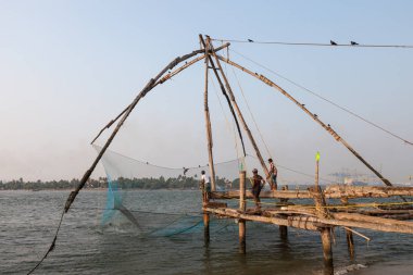Kochin, Hindistan-Şubat 24: Balıkçılar üzerinde 24 Şubat 2013 Kochin, Hindistan'da şehir noktasında. Hint balıkçı balıkçılık için geleneksel Çince ağ kullanma