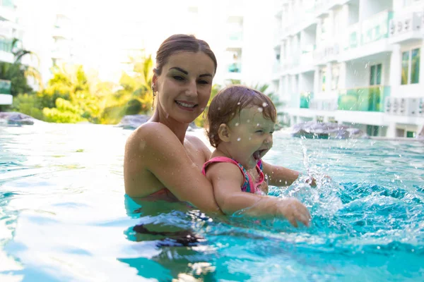 Mutlu anne kızı çerçevede bir Hindistan cevizi ağaçları ve peyzaj, sonsuzluk havuzu, çok düzeyli Yüzme Havuzu, sonsuzluk havuzu, açık havuzu havuzunda yüzmeyi öğretiyor