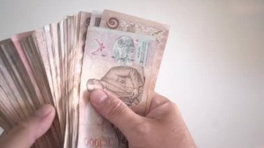 El thousansds Tayland Bahtı para sayma kapatın. İnsan Tay banknot, richman sayı sayma ve beyaz zemin üzerine ahşap masa üzerinde yüz baht faturaları tutan kapatın. Tayland yakın çekim