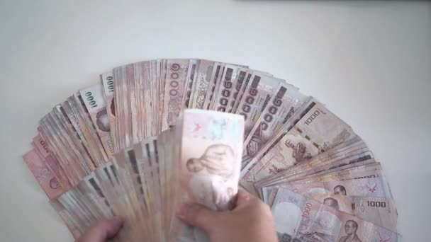 Close up hands counting of thousansds Thai baht money.Close up Human counting Thai banknote, richman count and holding hundred baht bills on wood table, on a white background. Close up of thailand — Stock Video