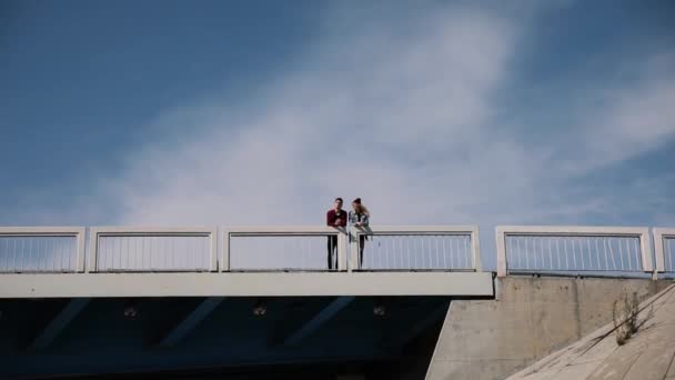 Gelukkige paar, in geruite overhemden, hand in hand en lopen op de brug van een auto op een zonnige zomerdag. Algemeen plan. Veel algemene plan — Stockvideo