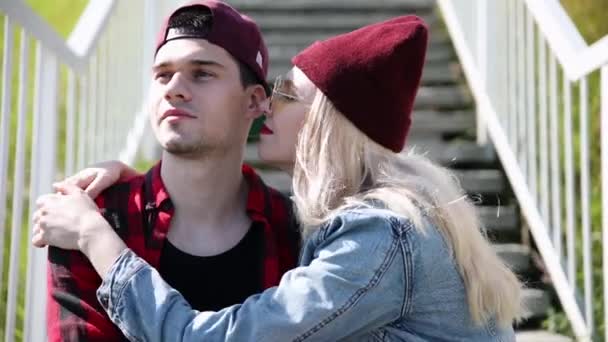 Happy couple, in plaid shirts, holding hands and walking on a car bridge on a sunny summer day. Sit on the steps of the bridge, gently look at each other. Close-up — Stock Video