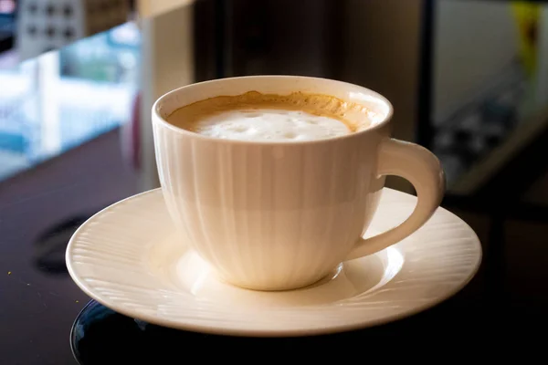 Fehér csésze kávé, egy fekete háttér csészealj. — Stock Fotó