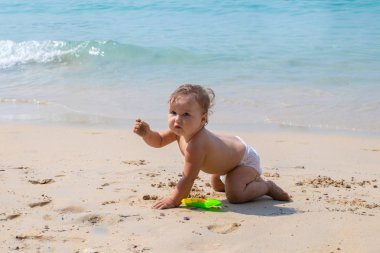 Yaz aylarında mavi denizin üzerinde oynayan mutlu çocuk. Bebek Plajda tarar ve oyuncaklarla çalış