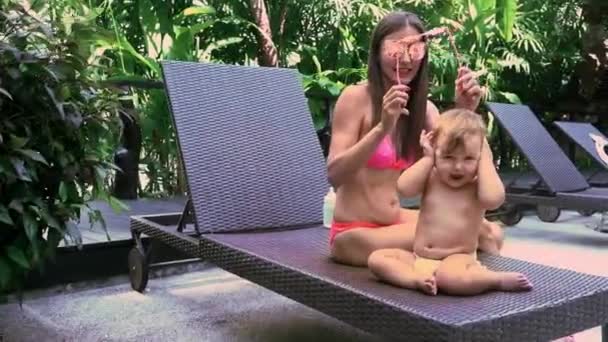 Mamá viste a su hija con gafas de sol, el bebé no quiere usarlas y se quita — Vídeo de stock