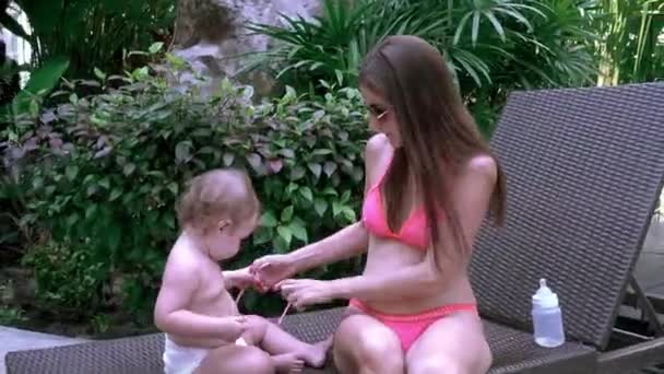 Мама одевает дочь солнцезащитные очки, ребенок не хочет носить их и снимает — стоковое видео