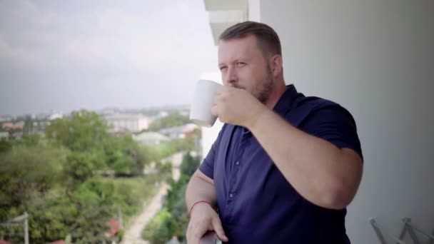 Uomo sul balcone che beve con una tazza e parla al telefono . — Video Stock
