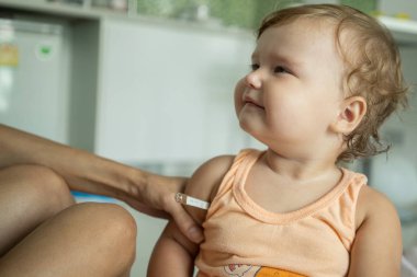 Çocuğu bir termometre koy. Sıcaklık ölçümü.