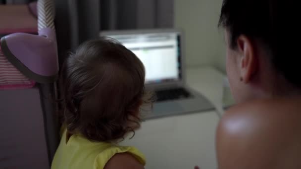 Werkende moeder met baby aan tafel. Drukke vrouw die werkt op laptop met baby op handen. Vrouwelijke freelance werken. Moderne moederschap — Stockvideo