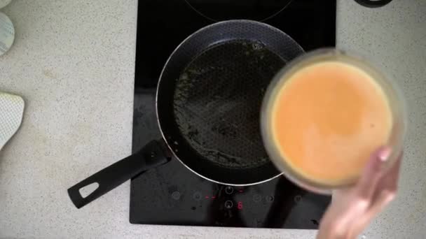 Женщины наливают смешанное молоко и яйца в кастрюлю для приготовления омлета на завтрак — стоковое видео