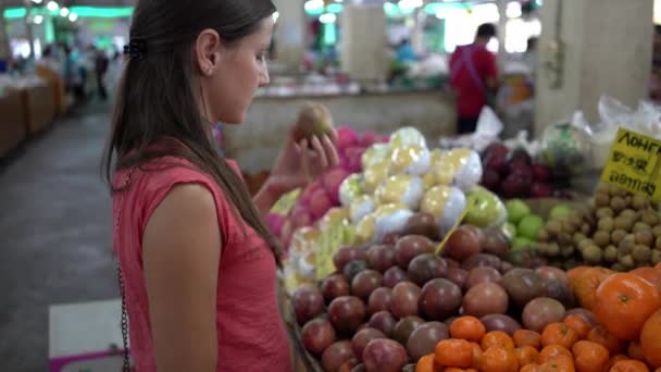 Девушка выбирает свежие фрукты на рынке . — стоковое видео