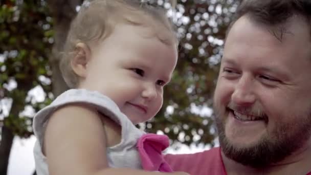 Primer plano de padre e hija jugando juntos. El joven padre gira a la hija en sus manos, ríe, juega. El concepto de una familia feliz — Vídeos de Stock