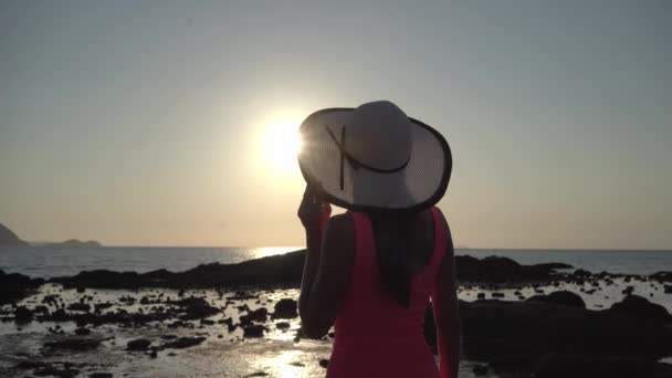 Dívka v klobouku procházek po pláži při západu slunce — Stock video