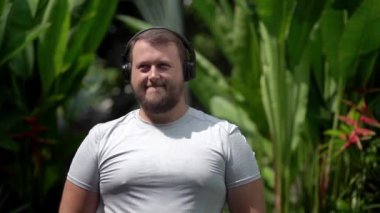 Sakallı komik adam giysilerini üzerinde koyar, müzik döner, enerjik müzik, dans etmek dinliyor. Yakın çekim