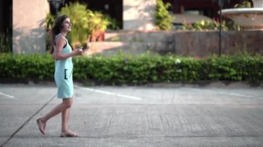 İletileri, Kentsel şehir sokak üzerinde yürürken kahve içme müzik yazarak akıllı telefon, kullanan güzel genç kadın