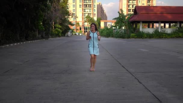 Vacker ung kvinna med hjälp av smart telefon, skriva meddelanden, lyssna på musik, dricker kaffe medan promenader på den urbana staden gatan — Stockvideo